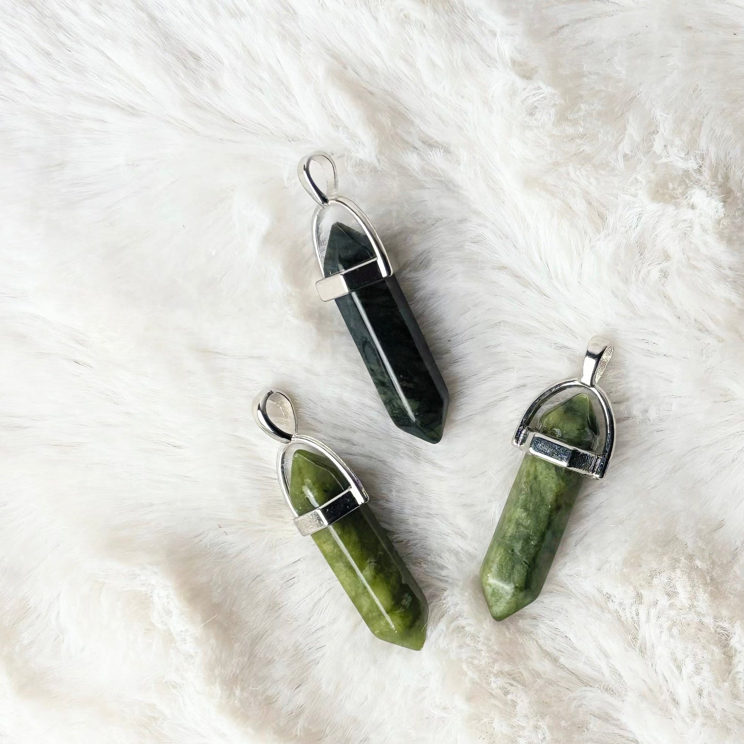 Three crystal pendants on a white fur surface