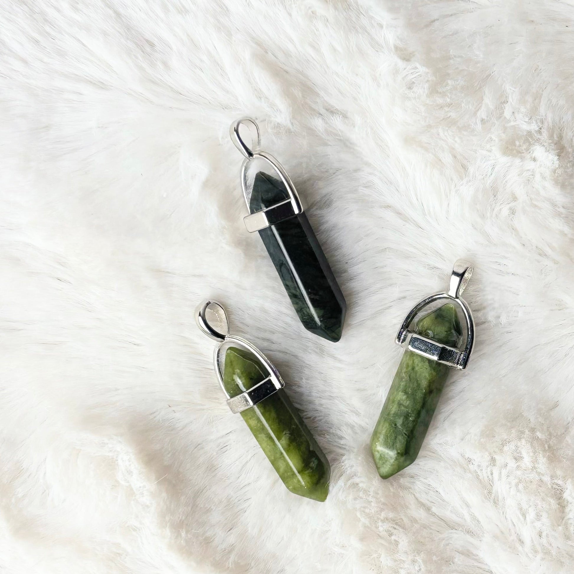 Three crystal pendants on a white fur surface