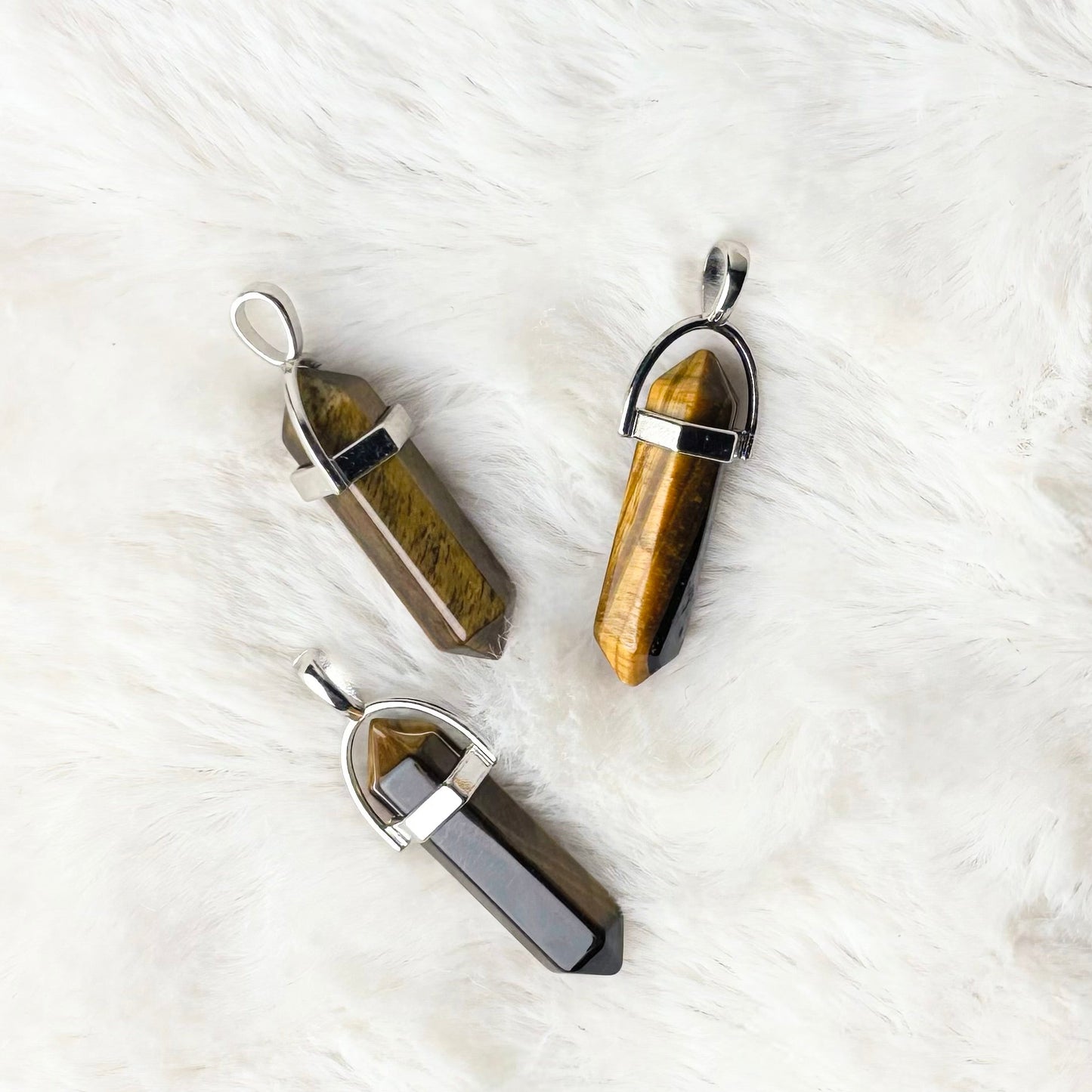 Three crystal pendants on a white fur surface