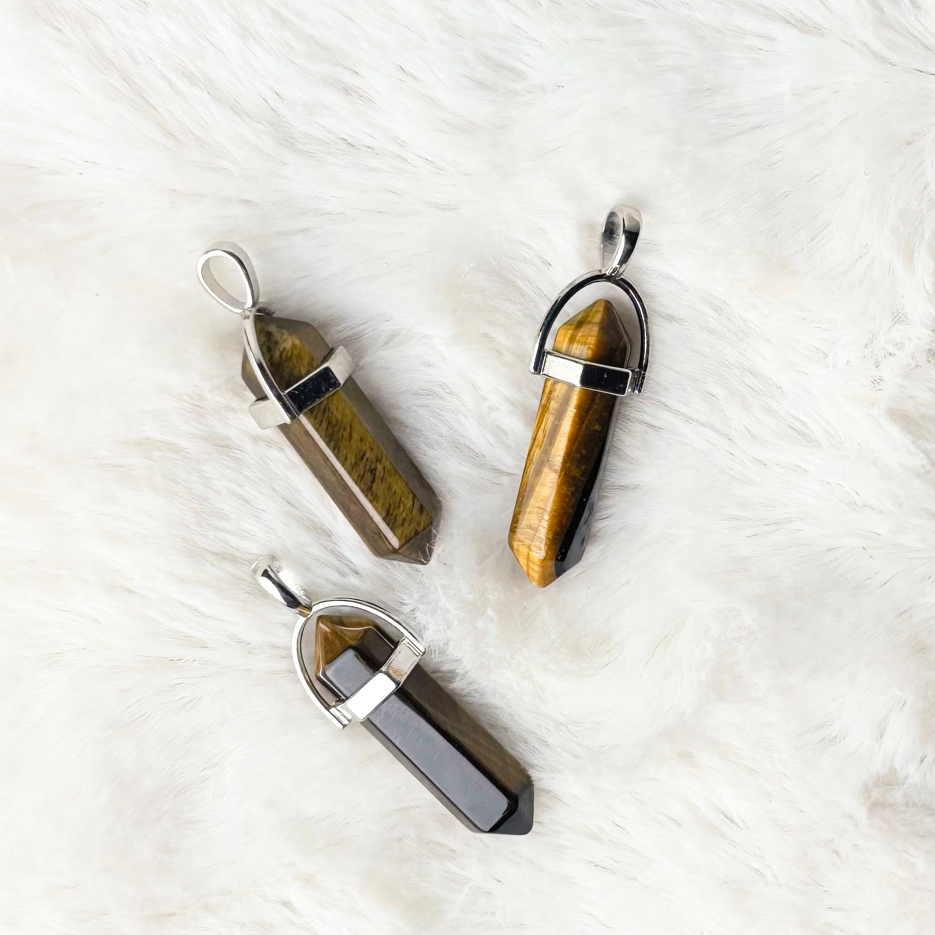 Three crystal pendants on a white fur surface