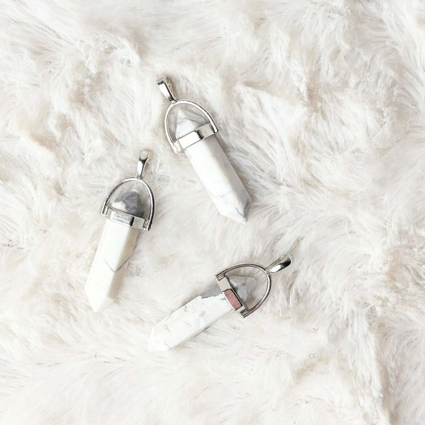 White stone pendants on a white fluffy surface