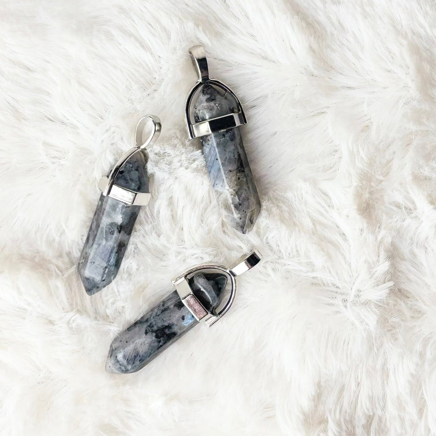 Three gray stone necklaces on a white fur surface
