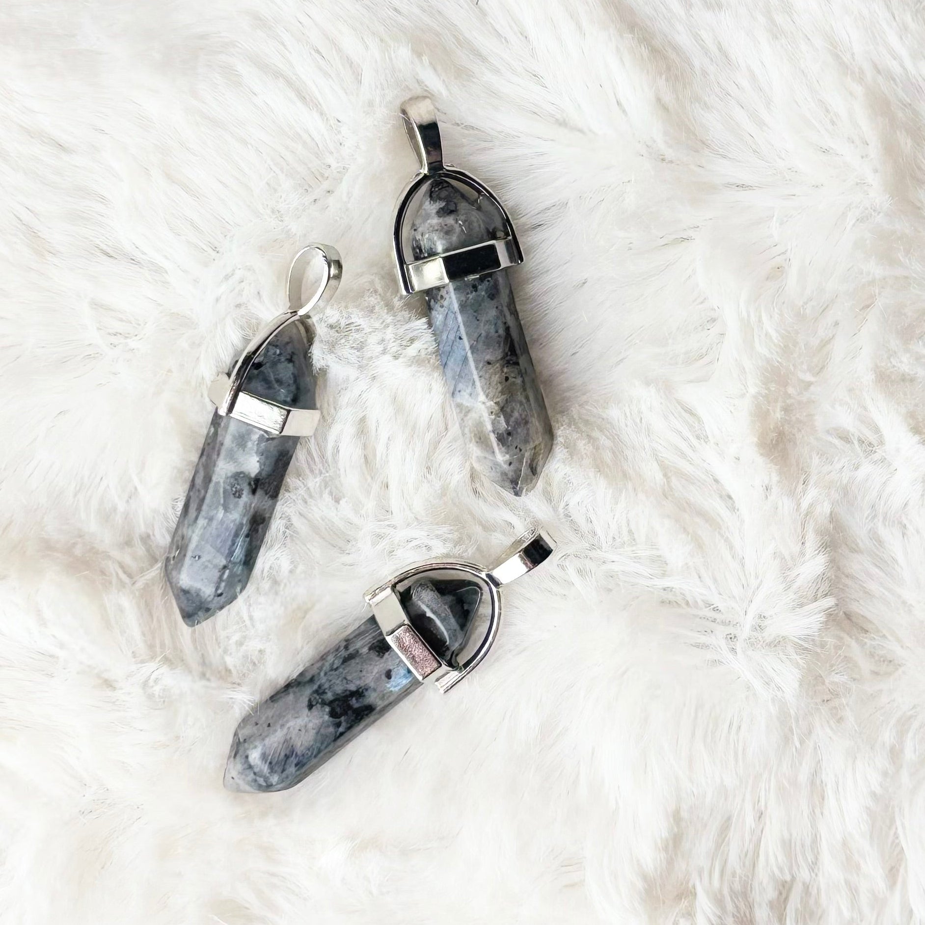 Three gray stone necklaces on a white fur surface