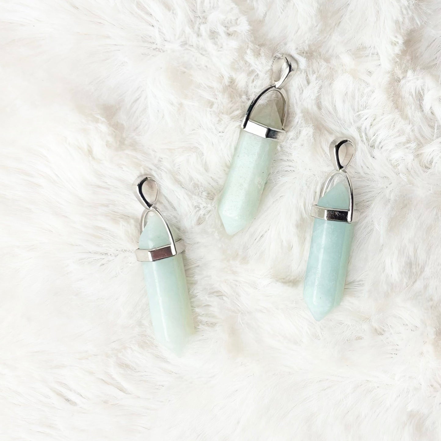 Three light blue earrings on a white fluffy surface