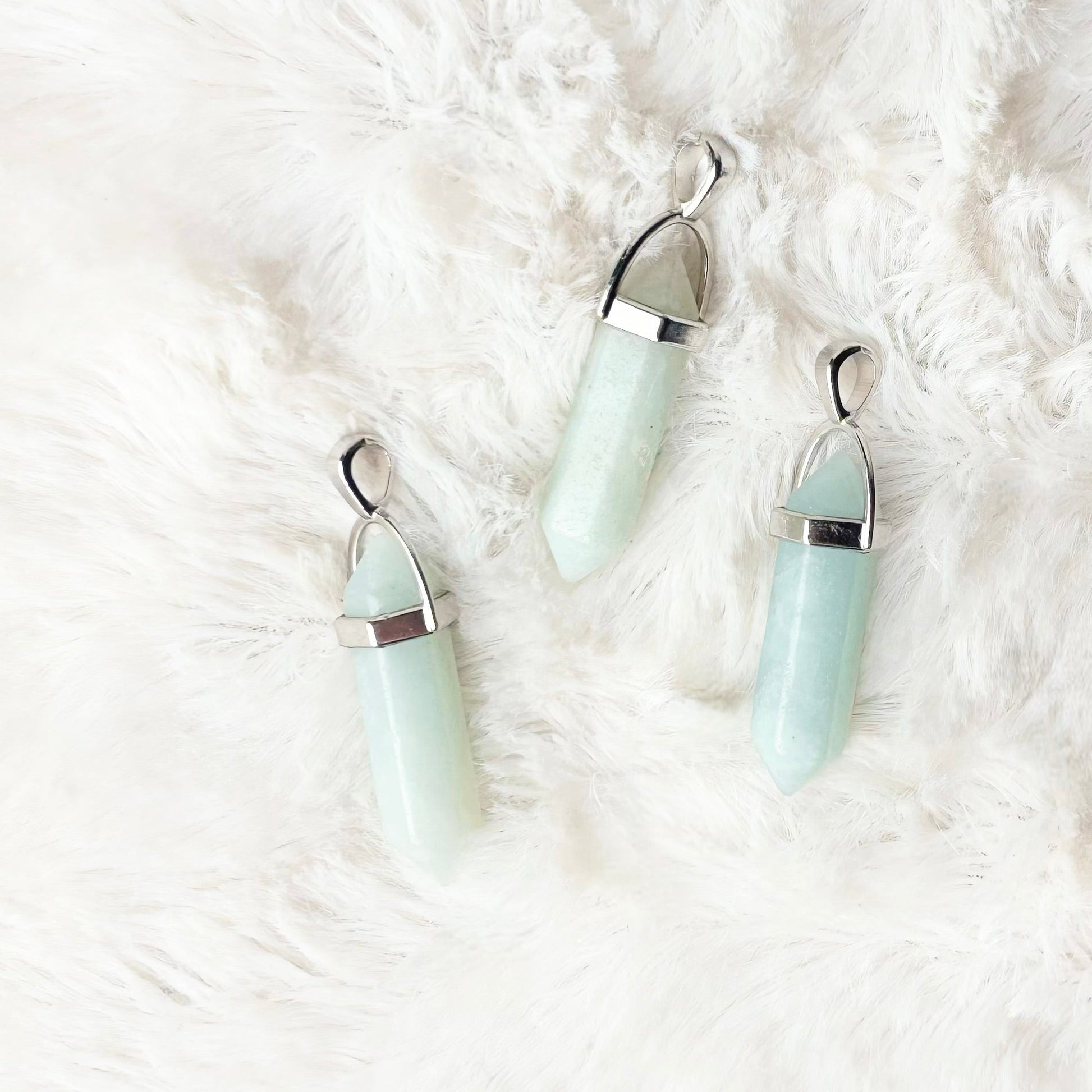 Three light blue earrings on a white fluffy surface