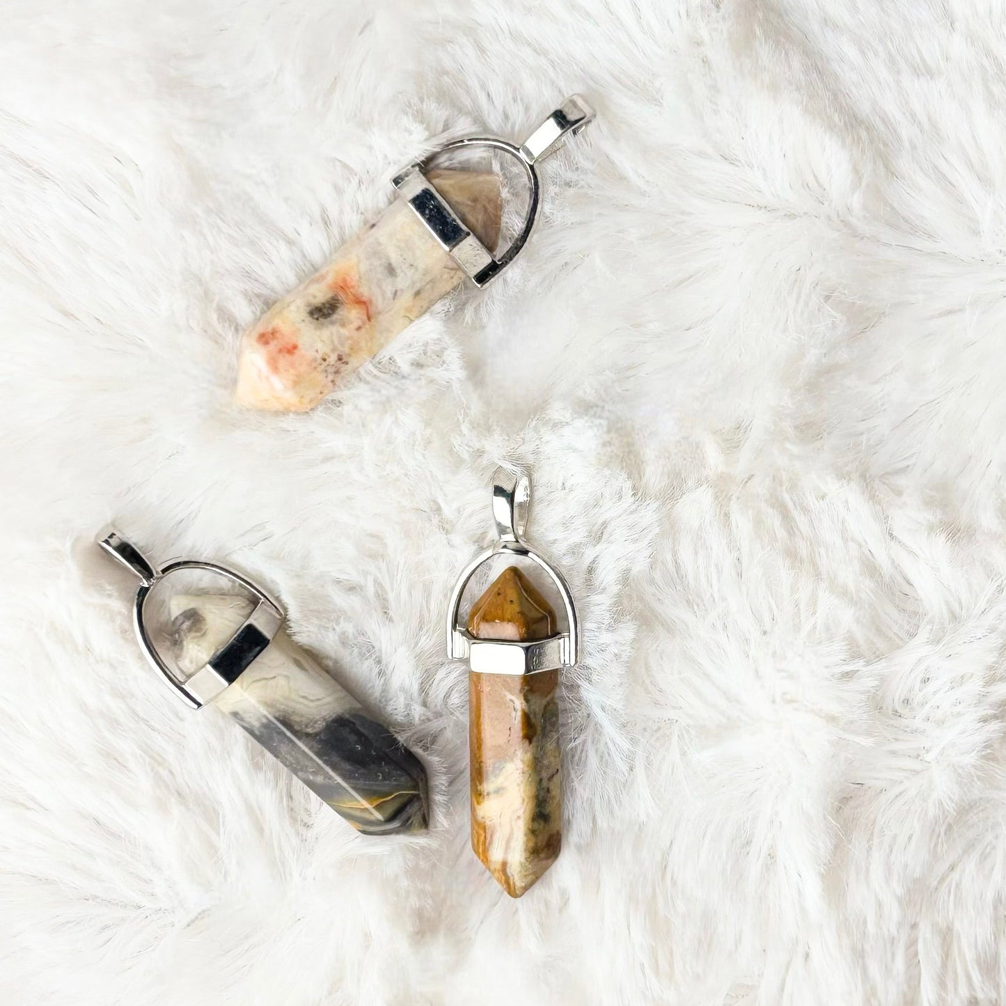 Three crystal pendants on a white fluffy surface