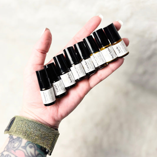 Hand holding a row of small black and white bottles against a neutral background