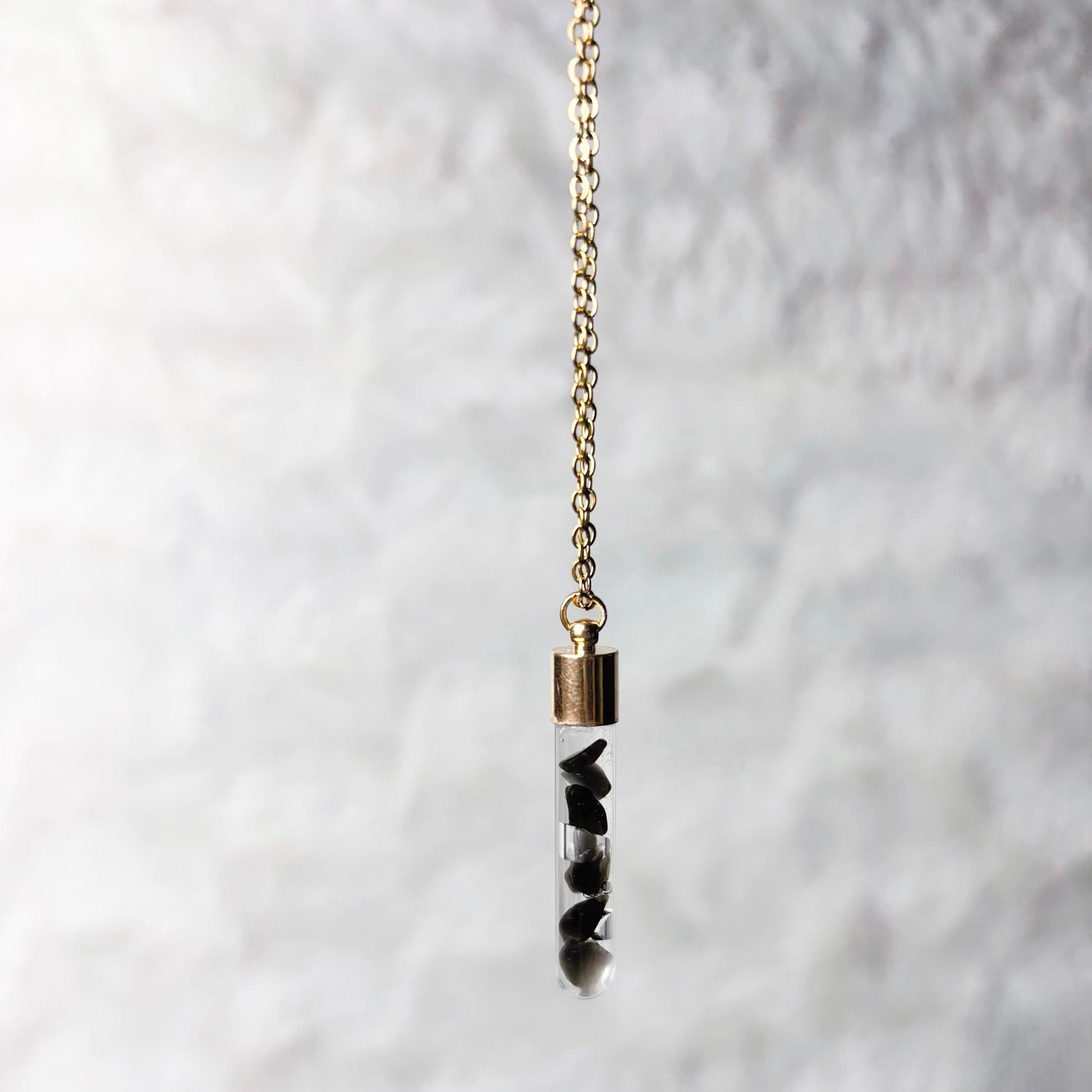 Necklace with a cylindrical pendant on a textured white background
