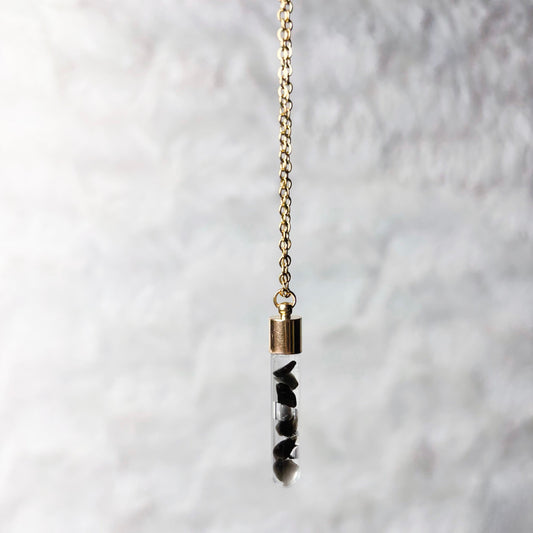 Necklace with a cylindrical pendant on a textured white background