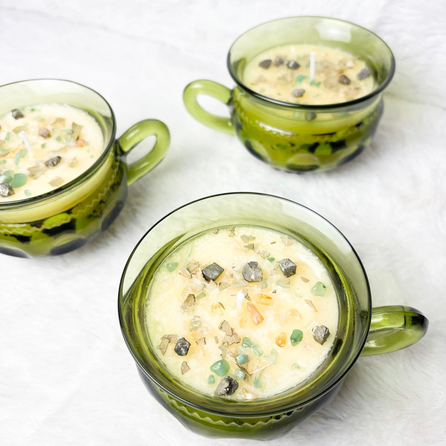 Candles with stones in a green glass cup