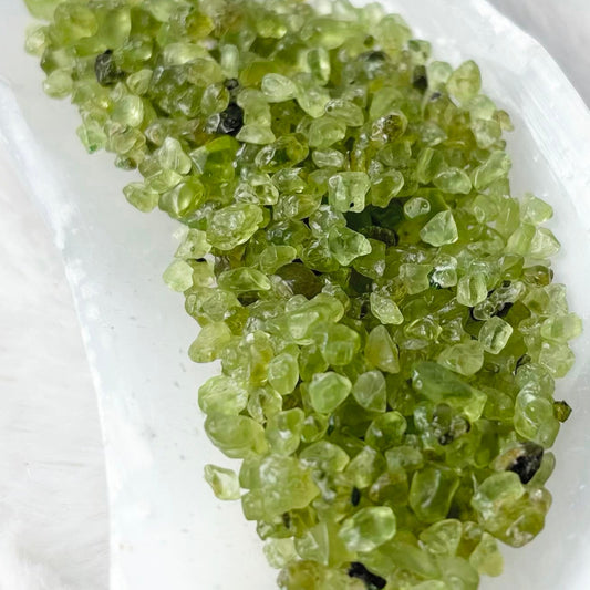 Green crystal bath salts in a white ceramic dish, set on a white faux fur background.