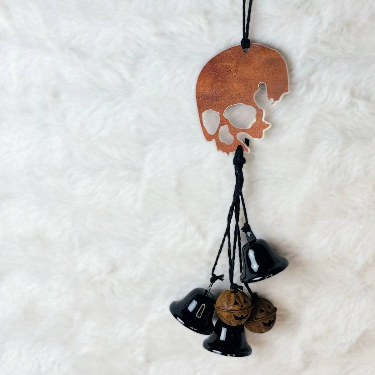 Rusty looking skull hanging with black jute, black bells, and rusty metal pumpkin bells