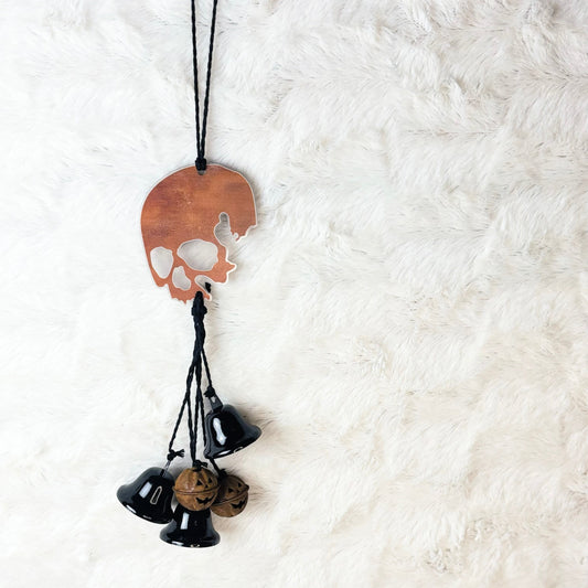 Rusty looking skull hanging with black jute, black bells, and rusty metal pumpkin bells