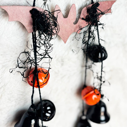 Metal bat hanging with black jute and black and orange pumpkin bells