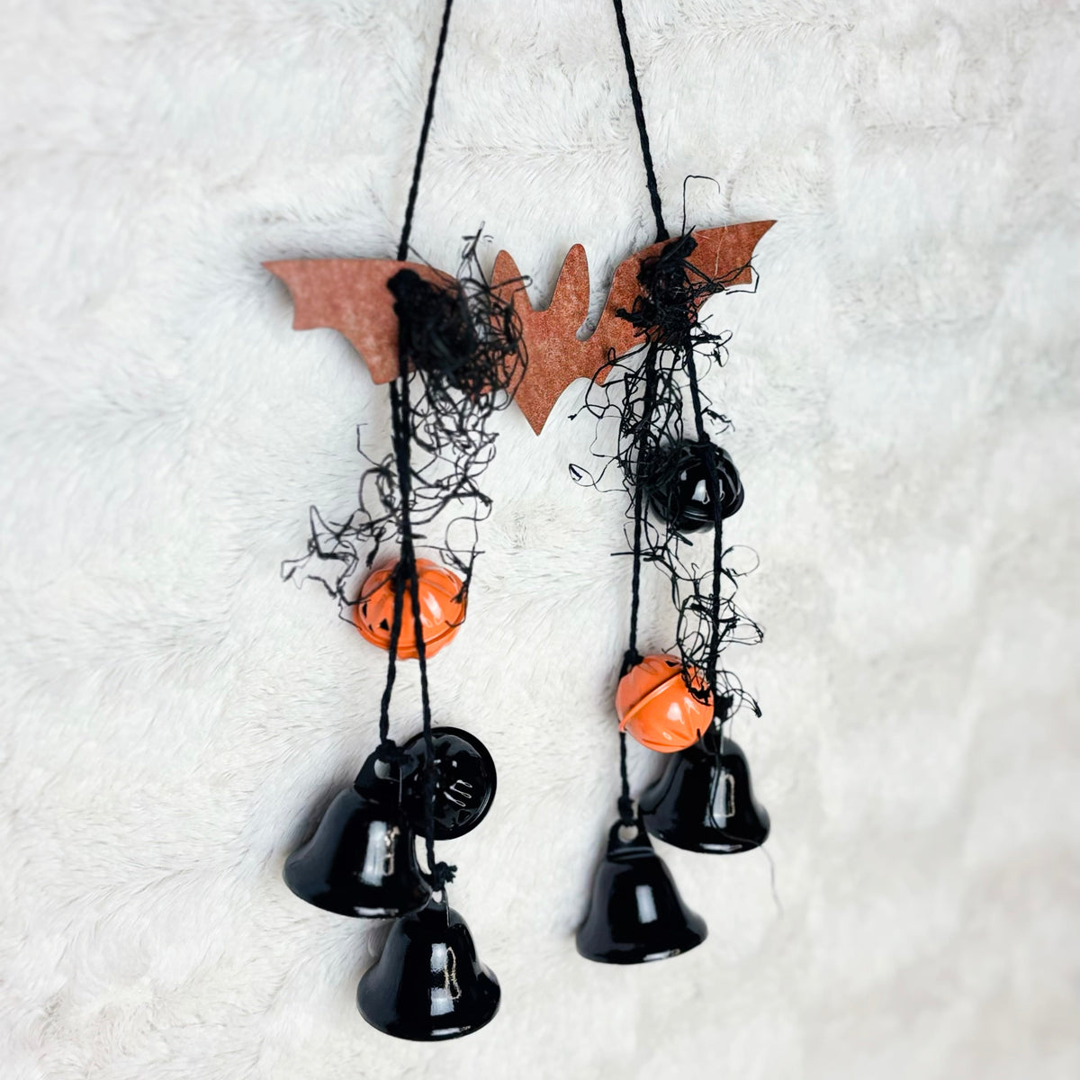 Metal bat hanging with black jute and black and orange pumpkin bells