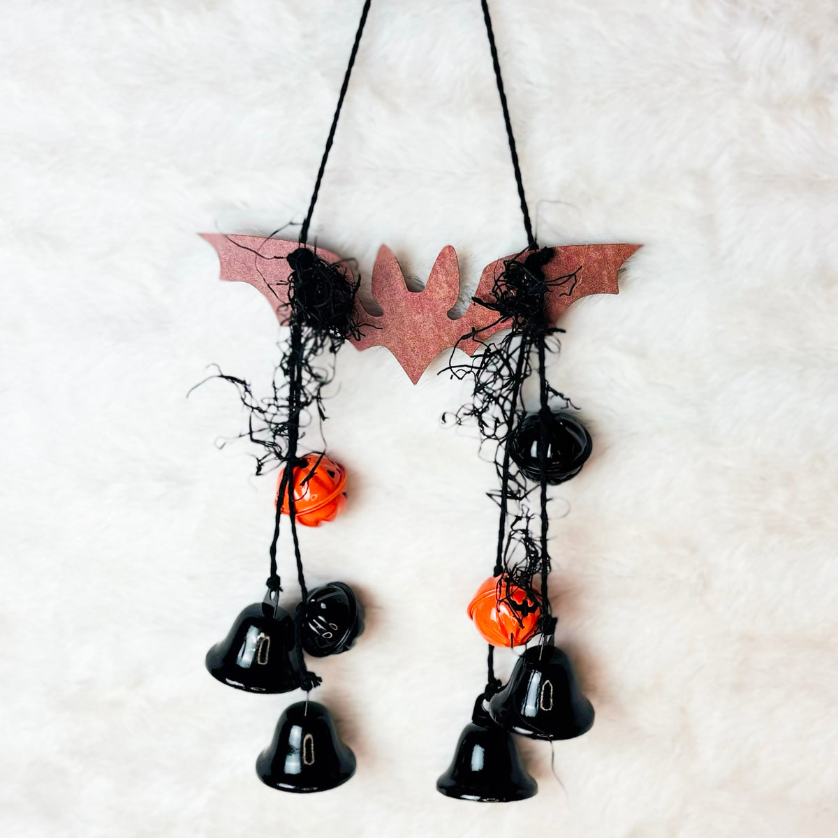 Metal bat hanging with black jute and black and orange pumpkin bells
