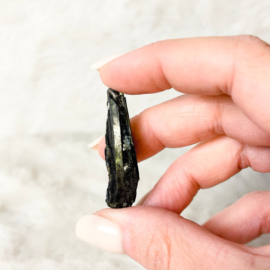 Hand holding a Vivianite specimen on a white background