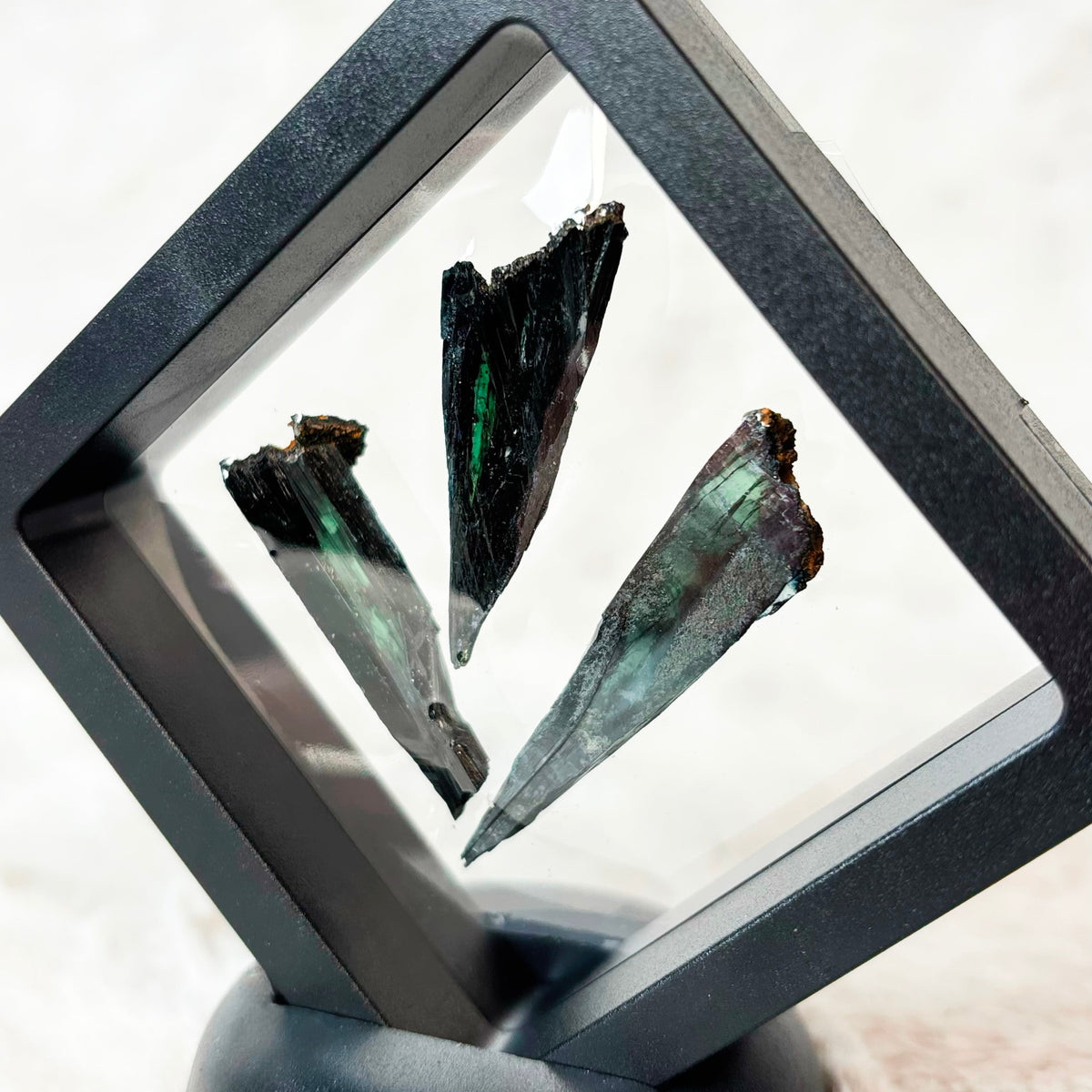 Three framed Vivianite specimens on a white background