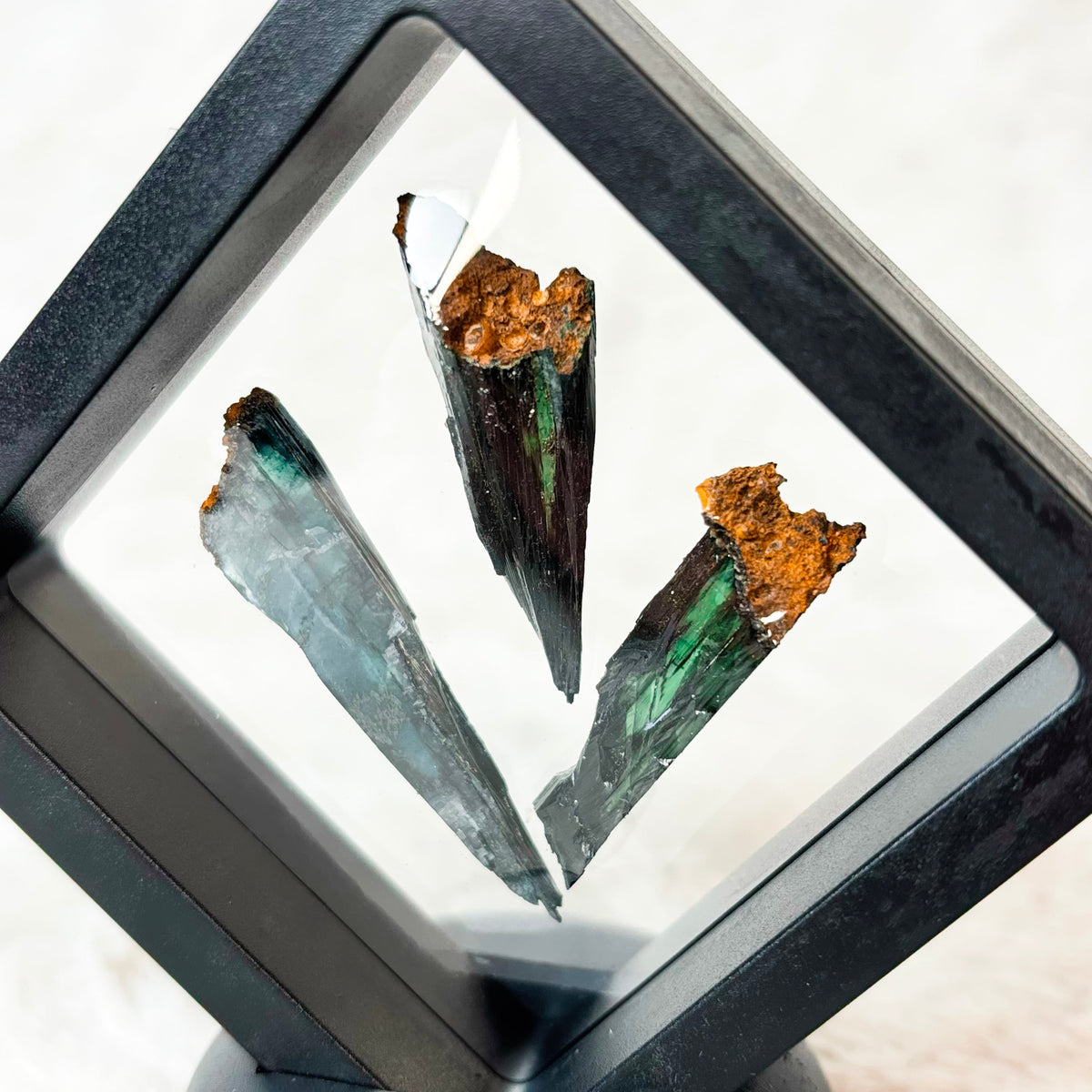Three framed Vivianite specimens on a white background