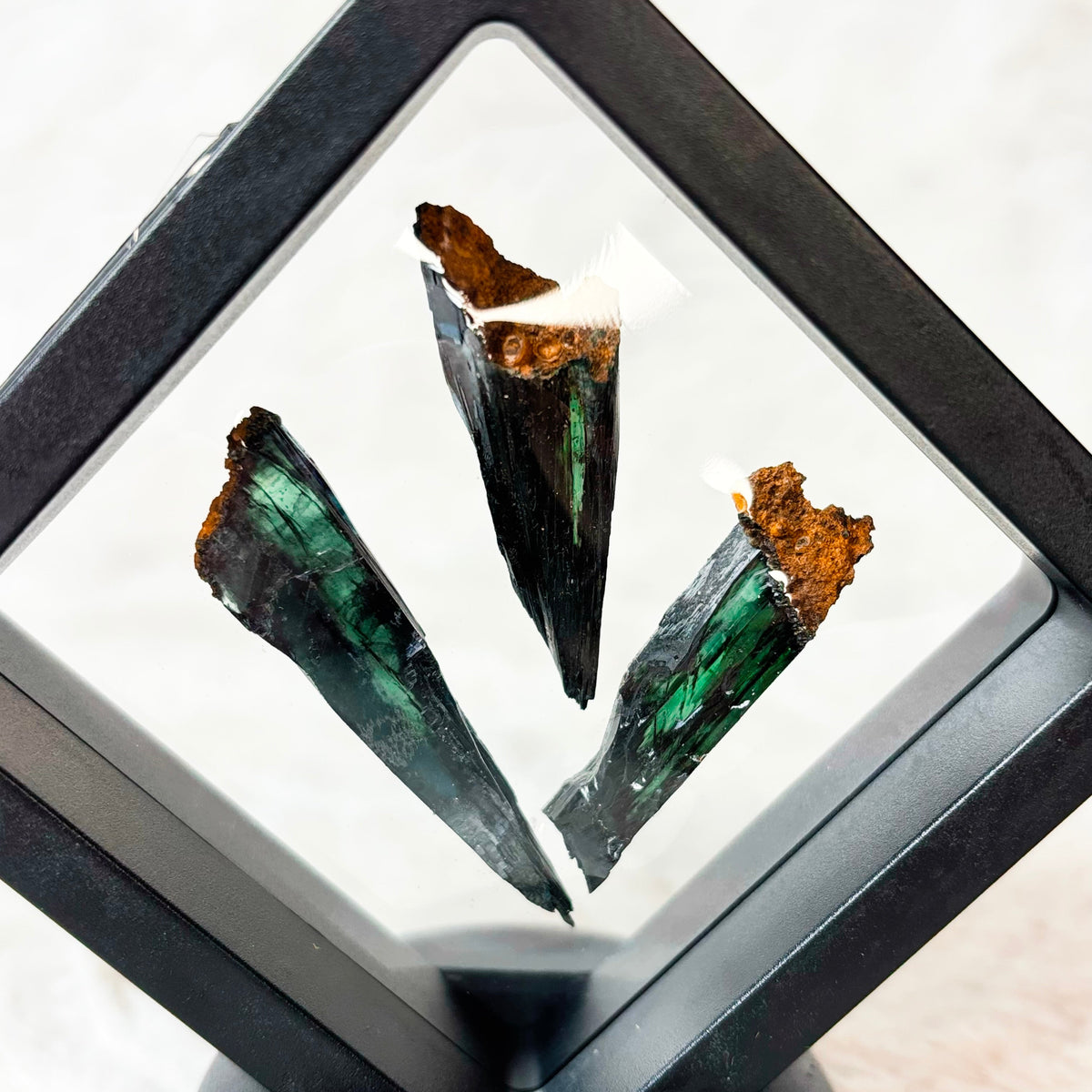Three framed Vivianite specimens on a white background